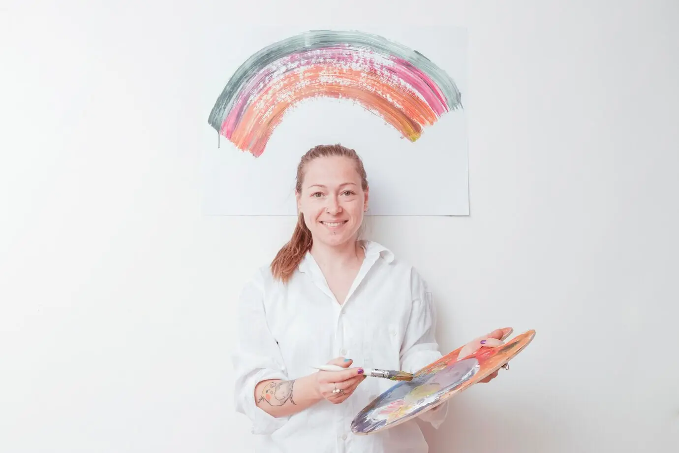 Cheerful painter with a palette and brush in a studio.